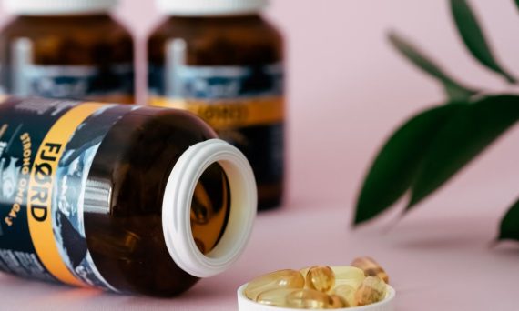 Close-up of omega-3 capsules and bottles on a pink background, ideal for health and wellness themes.